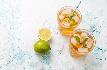 Iced tea with lime and ice on light background