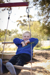 Happy preschool age boy playing on rope ladder at kindergarten 