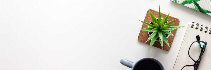 White office desk with copy space. Open notebook, glasses, coffee and succulent. View from above. Panoramic photo