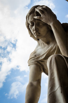 Primo piano della statua di una donna sofferente su una tomba del cimitero monumentale di Bologna