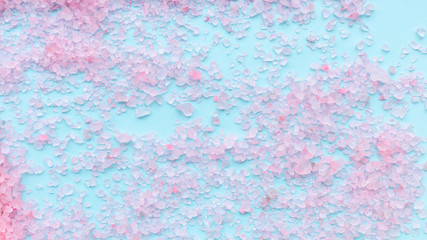 heap of large sprinkled crystals of pink sea salt closeup on a blue background with place for text. body care concept
