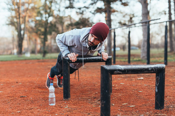handsome young man doing push ups outdoor in park