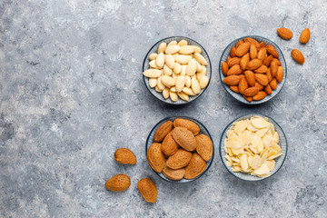 Raw fresh almonds with shell,without shelll,almond slices on grey concrete background,top view