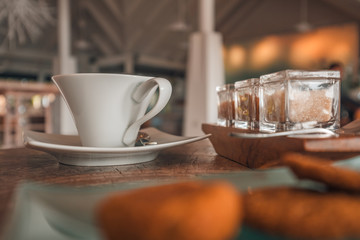 Cup of coffee on wooden table with selection of sugar and cookies
