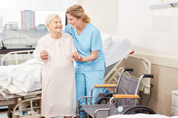 Nursing lady helps senior citizen to the wheelchair