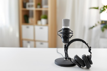 technology and audio equipment concept - headphones and microphone at home office or recording...