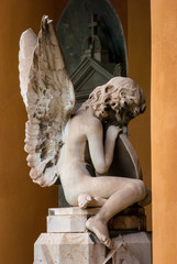 La statua di un angelo seduto su una tomba del cimitero monumentale di Bologna