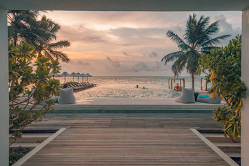 Swimming pool of luxury hotel, tropical beach sunset, island landscape. Beach resort with loungers and umbrellas and palm trees