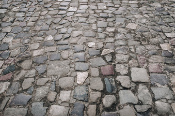 The gray paving stones close up. The texture of the old dark stone. Vintage, grunge. Road surface.