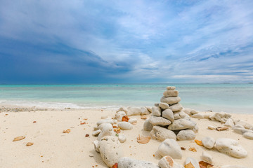 Fototapeta na wymiar Folded pyramid Zen pebble stones on the sea beach at dramatic sky