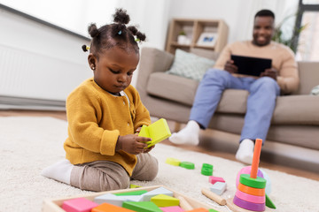 childhood and people concept - little african american baby girl playing with toy blocks at home