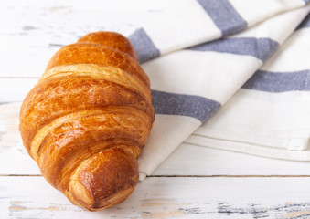 French rosy croissant on light napkin on white background. Bakery concept.