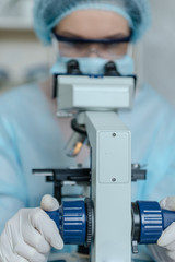 Female scientist studying coronavirus. The doctor looks through a microscope at a vaccine against coronavirus.