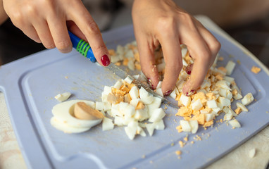 The girl cuts a boiled egg with a knife