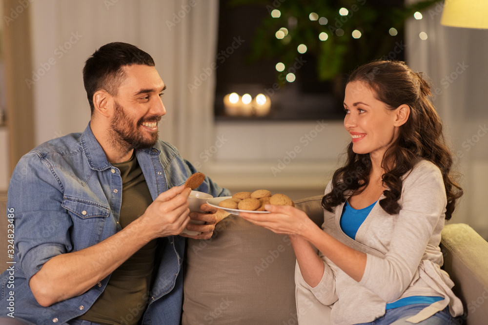 Canvas Prints leisure and people concept - happy couple drinking tea or coffee with cookies at home