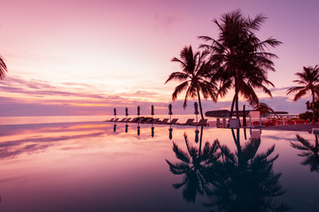 Beautiful poolside and sunset sky. Luxurious tropical beach landscape, deck chairs and loungers and...