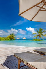 Summer beach vacation pool. Chaise lounge concept, luxury travel. Infinity oceanfront pool with...