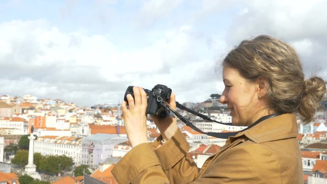 joyful woman stands on observation deck and takes photos
