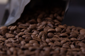 Coffee beans spill out of a black pack.