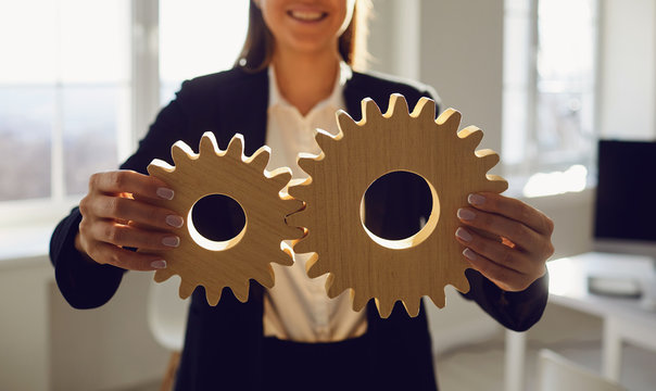 Faceless Businesswoman holding wooden gears in his hands in the office with windows.