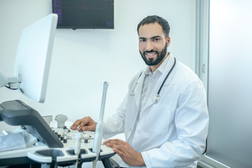 Fototapeta na wymiar Male doctor in white robesitting at the ultrasonic device