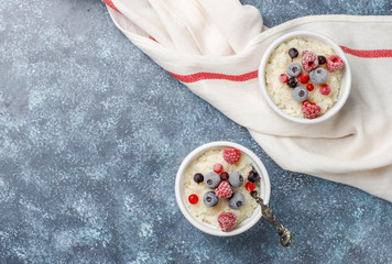 Rice pudding with frozen blueberries and raspberries in white bowl