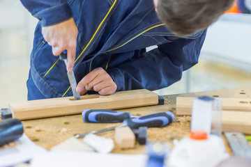 Professional man carpenter using chisel to carve wood on rough workbench at workshop. Design, carpentry, craftsmanship and handwork concept