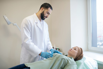 Dark-haired mammologist examining breasts of his patient