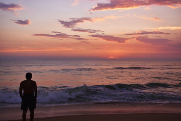 Fototapeta na wymiar a man standing in a beach during the sunset in ocean in Goa