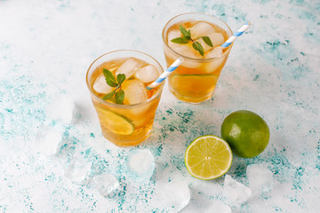 Iced tea with lime and ice on light background