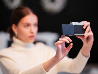Cute millennial woman or girl makes selfie on mirrorless camera to share on internet social media channels