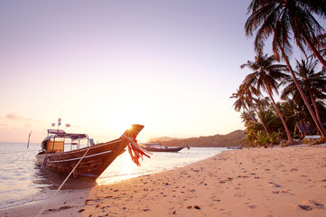 Beautiful sunset on the sea beach with traditional thai longtail boat.