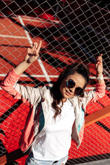 Trendy brunette young woman with bright smile dressed in casual modern clothes posing at the stadium.