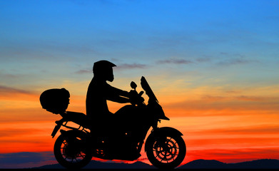 Obraz na płótnie Canvas Silhouette biker with his motorbike beside the natural lake and beautiful sunset sky.