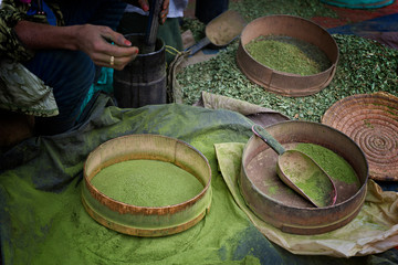 Woman making henna powder from dried henna leaves in a traditional way.
