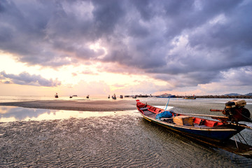 Beautiful sunset on the sea with traditional thai longtail boats.