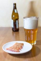 Beer in a glass on a wooden table in the background a bottle
