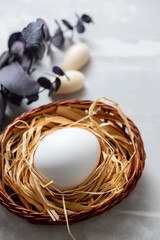 egg in small basket on light grey ceramic background