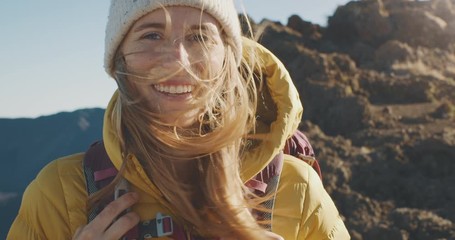 Portrait of a young adventurous woman smiling with her hair blowing in the wind, young woman on a backpacking trip outdoors