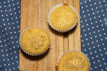 Aerial view of cinnamon muffins, cooked for class, on wooden board and polka dot tablecloth horizontal