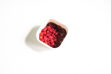 Fresh raspberries in metal bowl on white background. Colorful and juicy summer berry red. Flat layout, copy space.