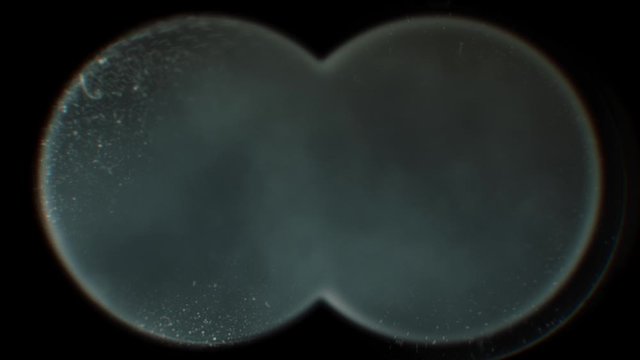 View through binoculars at black smoke coming from explosions or night fog.