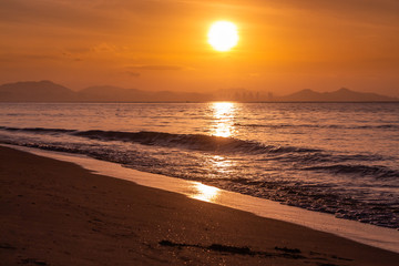 Naklejka na ściany i meble Beautiful orange sunrise is on the beach by the sea