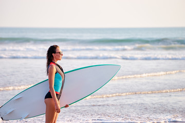 It's time for surfing! Hobby and vacation. Pretty young woman holding surf board on the sea shore.