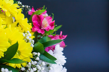 Bright bouquet of chrysanthemum lily green leaves on a dark background close-up. Festive floral background with space for text for mother's day, valentines day, march 8 or other holiday.