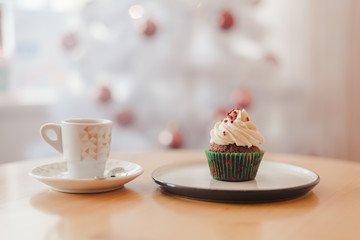Italian coffee Cup and cupcake on the table near the Christmas tree with white bokeh