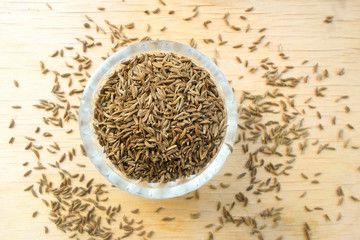 cumin in a glass cup on a wooden table
