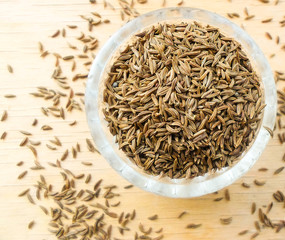 cumin in a glass cup on a wooden table
