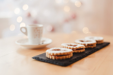 Italian coffee small Cup and cookie on the table near the Christmas tree with golden bokeh