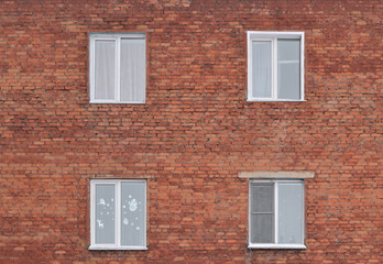 Fototapeta na wymiar Brick wall with four Windows. Background, texture. Fragment of a city building wall. Four white plastic Windows are arranged symmetrically.